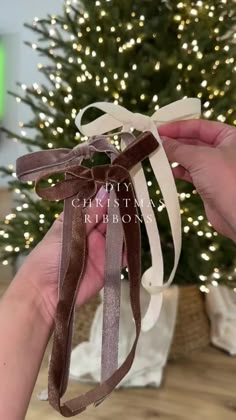 someone is holding a ribbon in front of a christmas tree