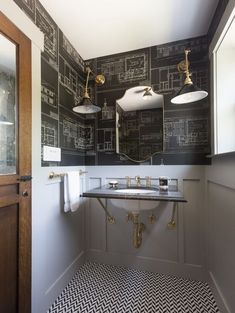 a bathroom with black and white wallpaper, gold fixtures and a double vanity mirror