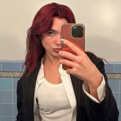 a woman taking a selfie with her cell phone in front of her face and wearing a suit jacket