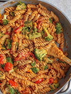 a skillet filled with pasta, broccoli and tomatoes