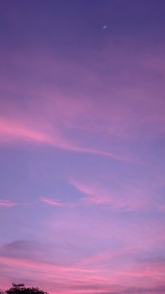 an airplane is flying in the sky at sunset or dawn with pink and purple clouds
