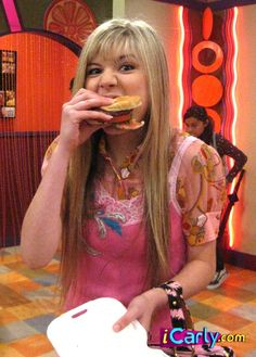 a woman is eating a doughnut while standing in front of a table with other people