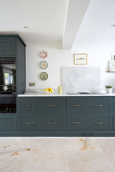 a kitchen with blue cabinets and marble counter tops in an open floorplan area