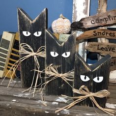 two black wooden cats with white eyes on them are sitting next to some wood signs