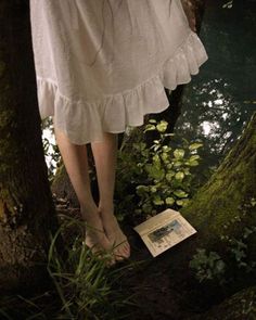 there is a woman's feet in the grass next to a book and trees