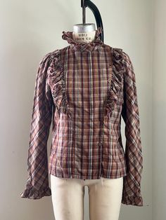 Vintage maroon, brown and blue plaid blouse. Unique design with ruffles and buttons up on left side.  Size medium Fall Plaid Cotton Blouse, Plaid Cotton Blouse For Fall, Plaid Ruffled Blouse For Work, Plaid Ruffle Blouse For Work, Plaid Long Sleeve Blouse With Ruffles, Fall Button-up Ruffled Shirt, Fall Ruffled Button-up Shirt, Fall Ruffle Button-up Shirt, Fall Button-up Shirt With Ruffles