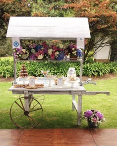 a table with flowers and desserts on it in the middle of a lawn area