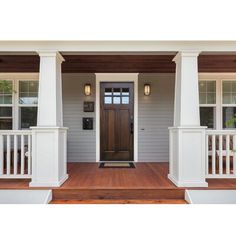 the front porch of a house with white pillars and wooden steps leading up to it