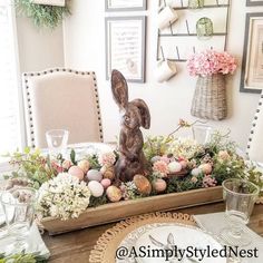 an easter table setting with bunny figurine in centerpiece and flowers on the side