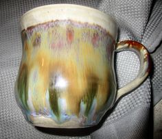 a coffee cup with an orange and yellow design on the inside is sitting on a gray surface