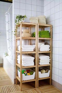 a wooden shelf filled with lots of white towels and other bathroom items next to a tiled wall