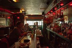 two people sitting at a bar with drinks in front of them and bottles on the counter