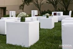 white chairs and vases with flowers in them on the grass outside an office building