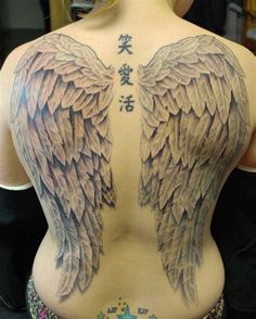 the back of a woman's body with angel wings tattooed on her upper part