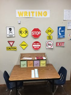 a table and chairs in front of a bulletin board with various signs on the wall