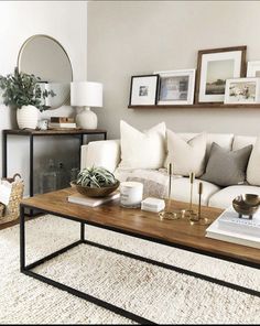 a living room with white couches and pictures on the wall above it, along with a coffee table