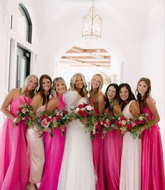 a group of women standing next to each other wearing dresses and holding bouquets in their hands