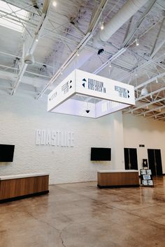 an empty room with two televisions on the wall and some signs hanging from the ceiling