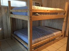 two bunk beds in a small room with tile flooring and wood paneled walls