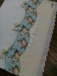 an old table cloth with flowers and shells on the edge is laying on a wooden floor