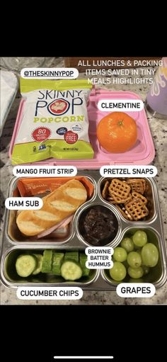 the lunch box is full of different foods and snacks, including crackers, cucumber chips, oranges, and other items