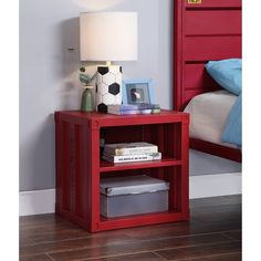 a red book shelf next to a bed with a lamp and pictures on top of it