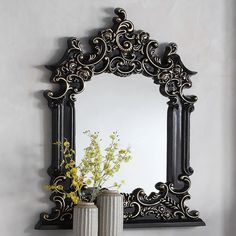 there is a vase with flowers in it and a mirror on the wall