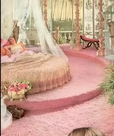 there is a woman laying on a bed in the room with pink carpet and curtains