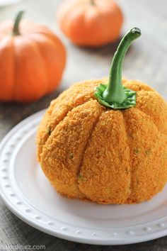 a pumpkin shaped cake sitting on top of a white plate next to bowls of vegetables