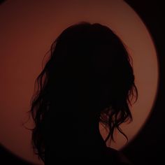 the silhouette of a woman's head in front of a circular object with long hair