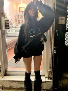 a woman standing in front of a window wearing boots