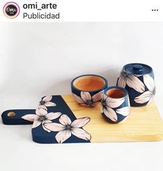 three cups and one teapot are sitting on a cutting board