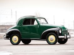 an old green car parked in a parking lot