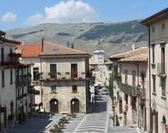 an empty street with buildings and mountains in the background