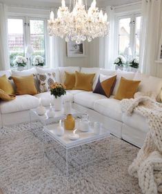 a living room filled with white furniture and lots of pillows on top of it's couches