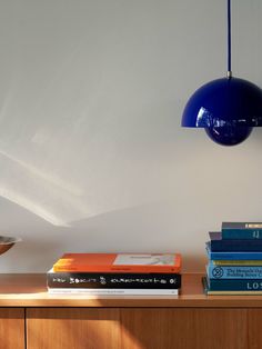 a table topped with books and a blue light hanging from it's sideboard