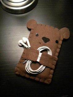 a cell phone case made to look like a bear with earbuds in it