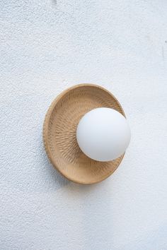 an egg sitting on top of a wooden bowl next to a white wall and floor