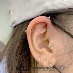 a woman with ear piercings wearing a baseball cap and looking at the side of her ear