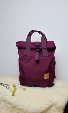 a purple bag sitting on top of a white blanket