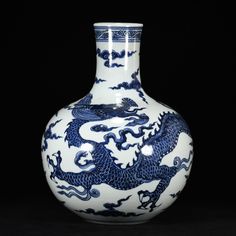 a blue and white vase with a dragon design on the front, against a black background