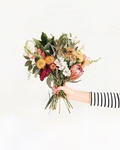 a woman holding a bouquet of flowers in her hand