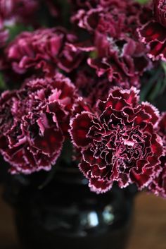 a black vase filled with red flowers on top of a table