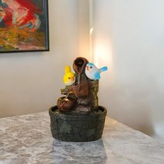 there is a sculpture on the table with two birds sitting on it and another bird in the background