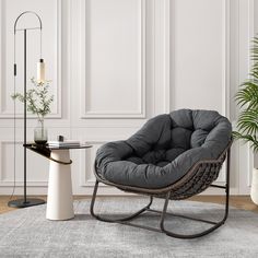 a living room with a chair, table and potted plant on the floor next to it