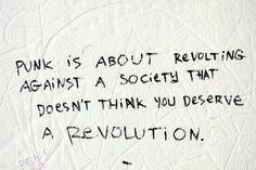 graffiti written on the side of a white wall with black writing that reads punk is about revealing against a society that doesn't think you deserves a revolution