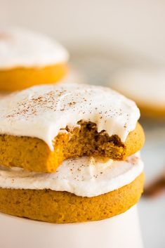 two frosted pumpkin cookies stacked on top of each other