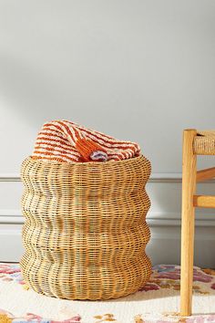 a woven basket sitting on top of a rug next to a wooden chair