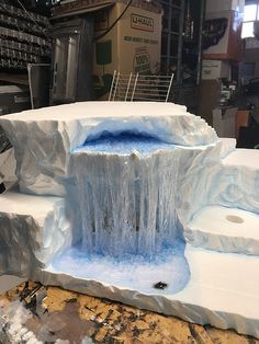 an ice sculpture in the shape of a waterfall with blue water flowing down it's sides