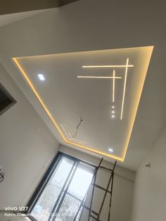 a room with a ladder and some lights on the ceiling in front of a window